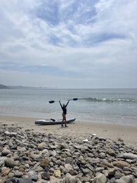 a person standing on a beach with a surfboard