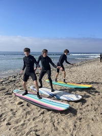 three people standing on the beach with surfboards