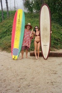 two people standing on a beach holding surfboards